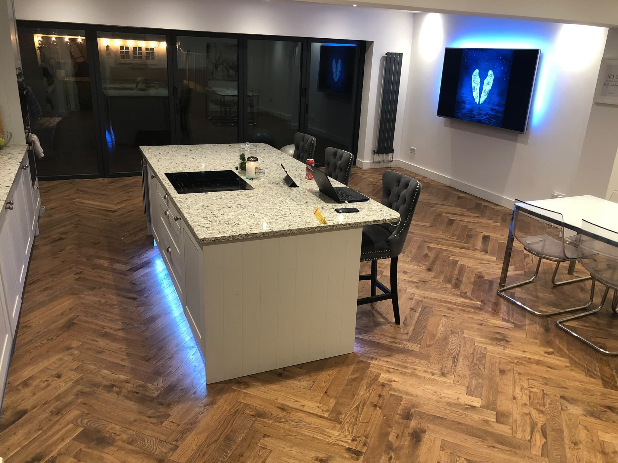 New kitchen with a stone-topped island, LED plinth lighting and a herringbone floor